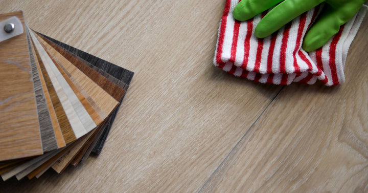 A gloved hand moves a red and white striped cloth across vinyl sheeting beside swatches of vinyl tile samples.