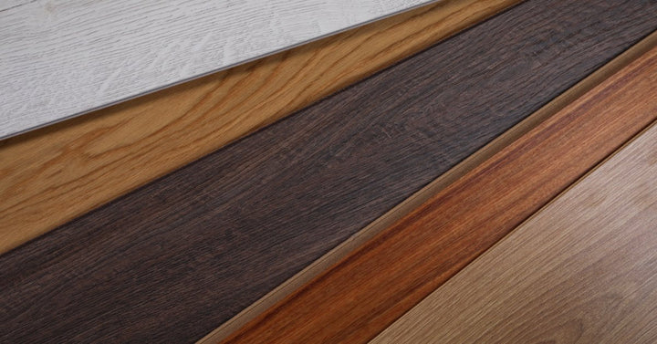 Five wooden floor planks sit side by side in various shades of gray, warm, dark, reddish, and natural wood tones.